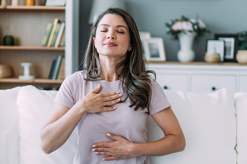 woman with hand on chest and stomach with eyes closed