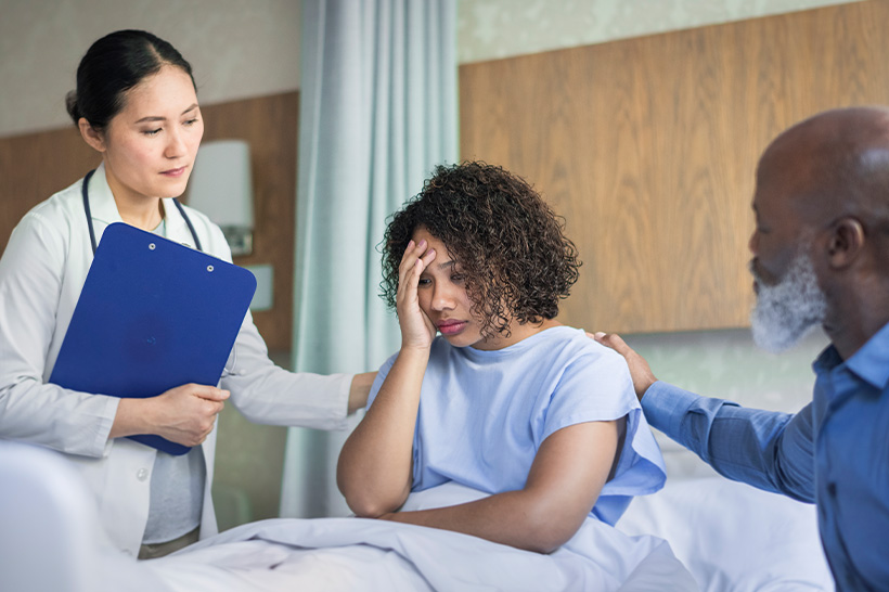 A doctor stands next to a woman in a hospital bed
